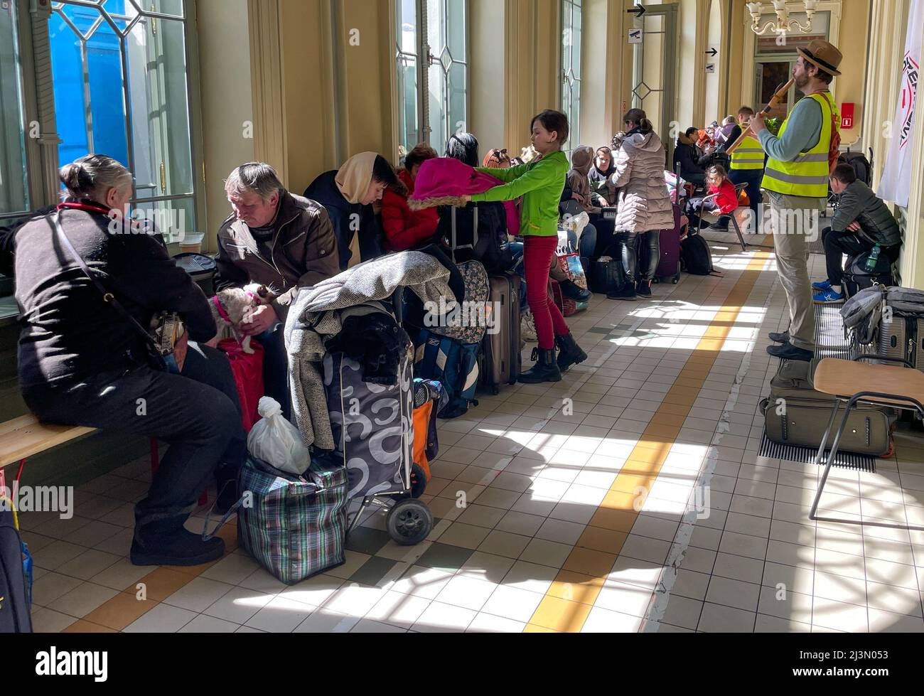 Przemysl, Polonia. 8th Apr 2022. Un volontario della Caritas attraversa il corridoio pieno di rifugiati ucraini, come Fabian, un volontario francese compassionevole e soulful che ha praticato il buddismo per oltre 20 anni, gioca il suo flauto per cercare di sollevare gli spiriti degli ucraini devastati dalla guerra di Putin, che formano lunghe code sui banchi rigidi dove molti attenderanno molte ore, in attesa di salire a bordo di treni che li allontaneranno dal terrore che hanno vissuto per la sicurezza di nuove case. (Credit Image: © Amy Katz/ZUMA Press Wire) Credit: ZUMA Press, Inc./Alamy Live News Foto Stock
