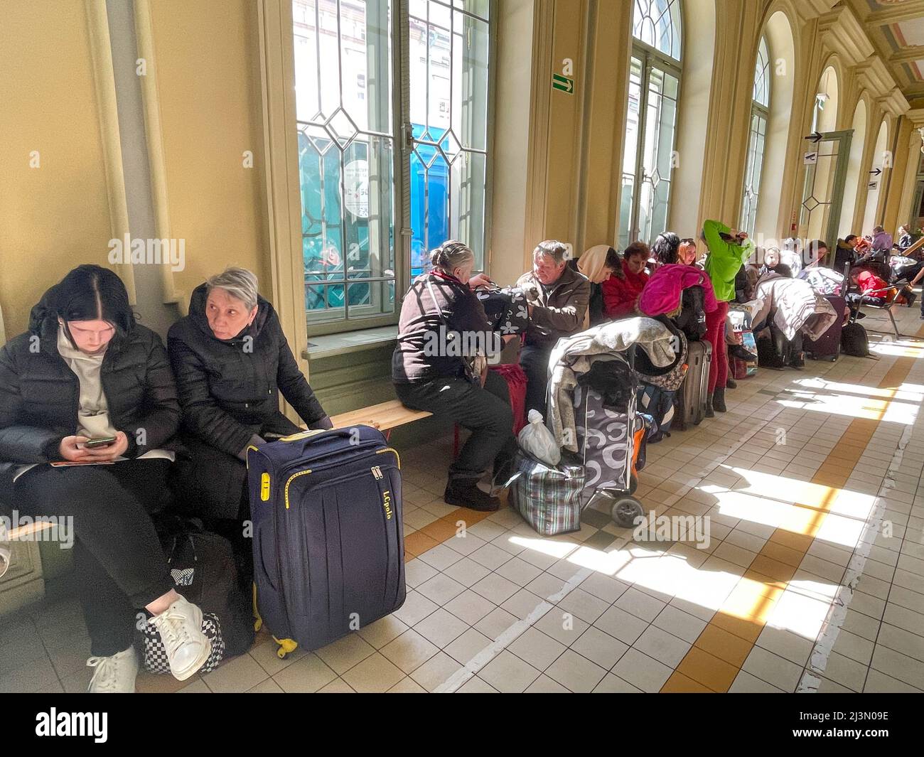 Przemysl, Polonia. 8th Apr 2022. Un volontario della Caritas attraversa il corridoio pieno di rifugiati ucraini, come Fabian, un volontario francese compassionevole e soulful che ha praticato il buddismo per oltre 20 anni, gioca il suo flauto per cercare di sollevare gli spiriti degli ucraini devastati dalla guerra di Putin, che formano lunghe code sui banchi rigidi dove molti attenderanno molte ore, in attesa di salire a bordo di treni che li allontaneranno dal terrore che hanno vissuto per la sicurezza di nuove case. (Credit Image: © Amy Katz/ZUMA Press Wire) Credit: ZUMA Press, Inc./Alamy Live News Foto Stock