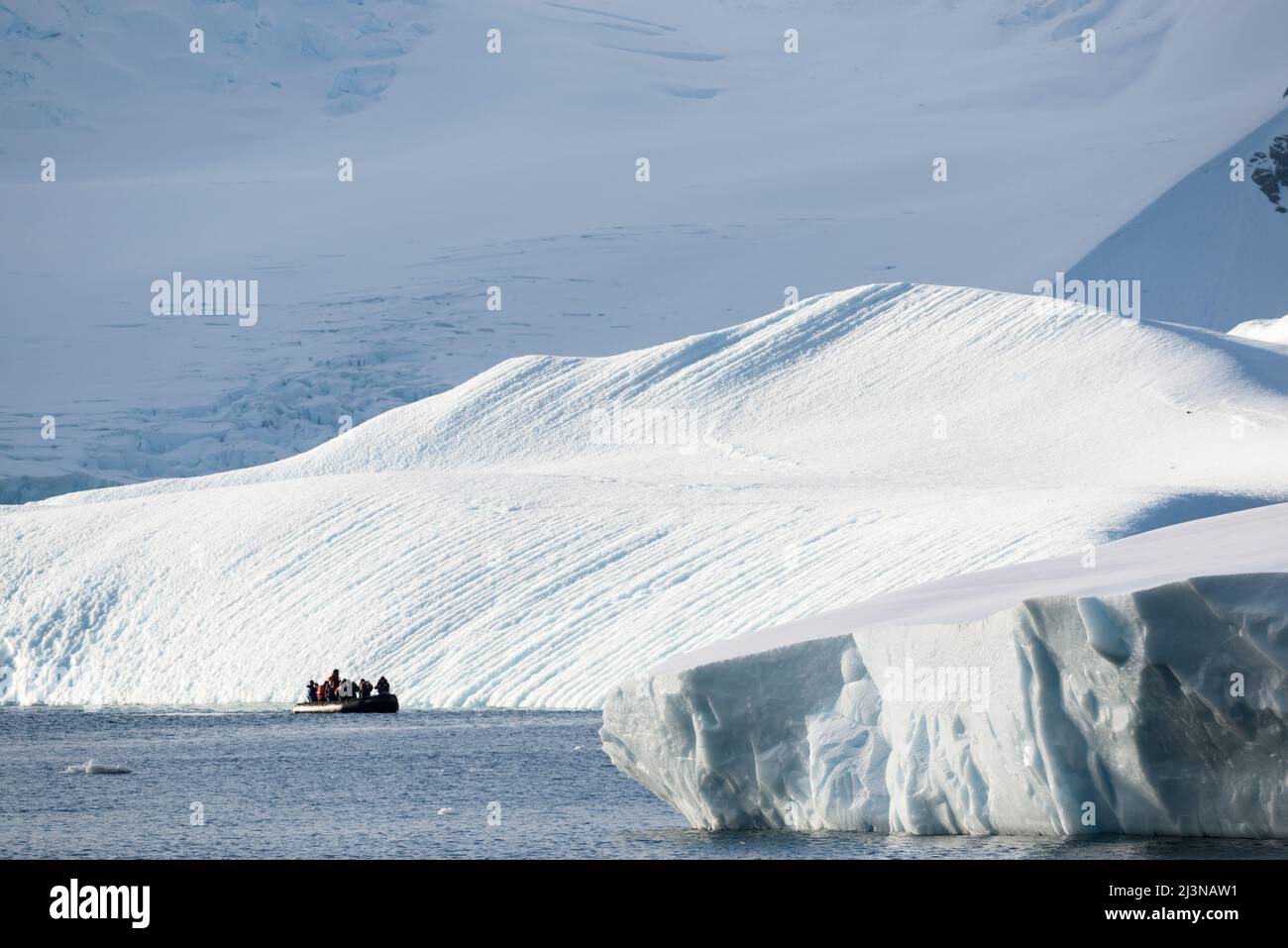 Luce del pomeriggio, i turisti in uno Zodiaco osservano il paesaggio intorno alla Baia di Marguerite, a sud del cerchio Antartico. Antartide, Foto Stock