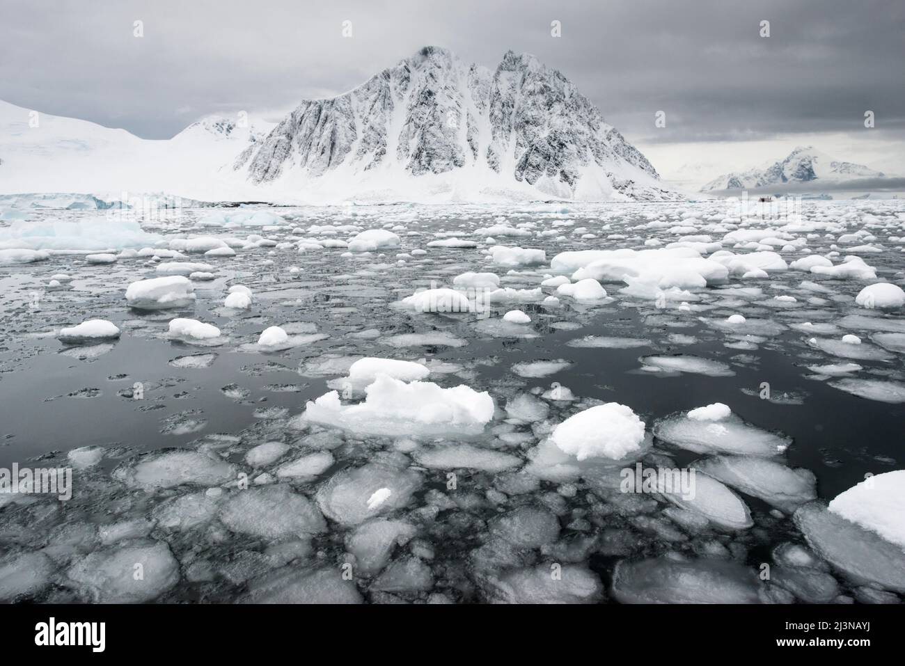 Fine estate, mare e paesaggio all'interno del cerchio Antartico, con i turisti in uno Zodiaco in lontananza. Al largo di Neny Island all'interno della baia di Marguerite Foto Stock