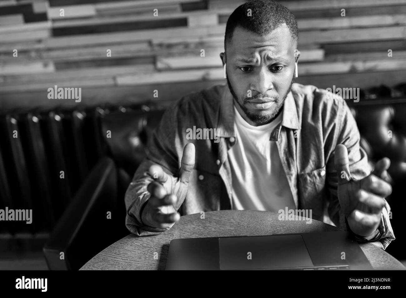 Ritratto bianco-nero di un giovane uomo d'affari afroamericano pensivo, guardando lo schermo del laptop, negoziando un piano d'affari. L'imprenditore Foto Stock