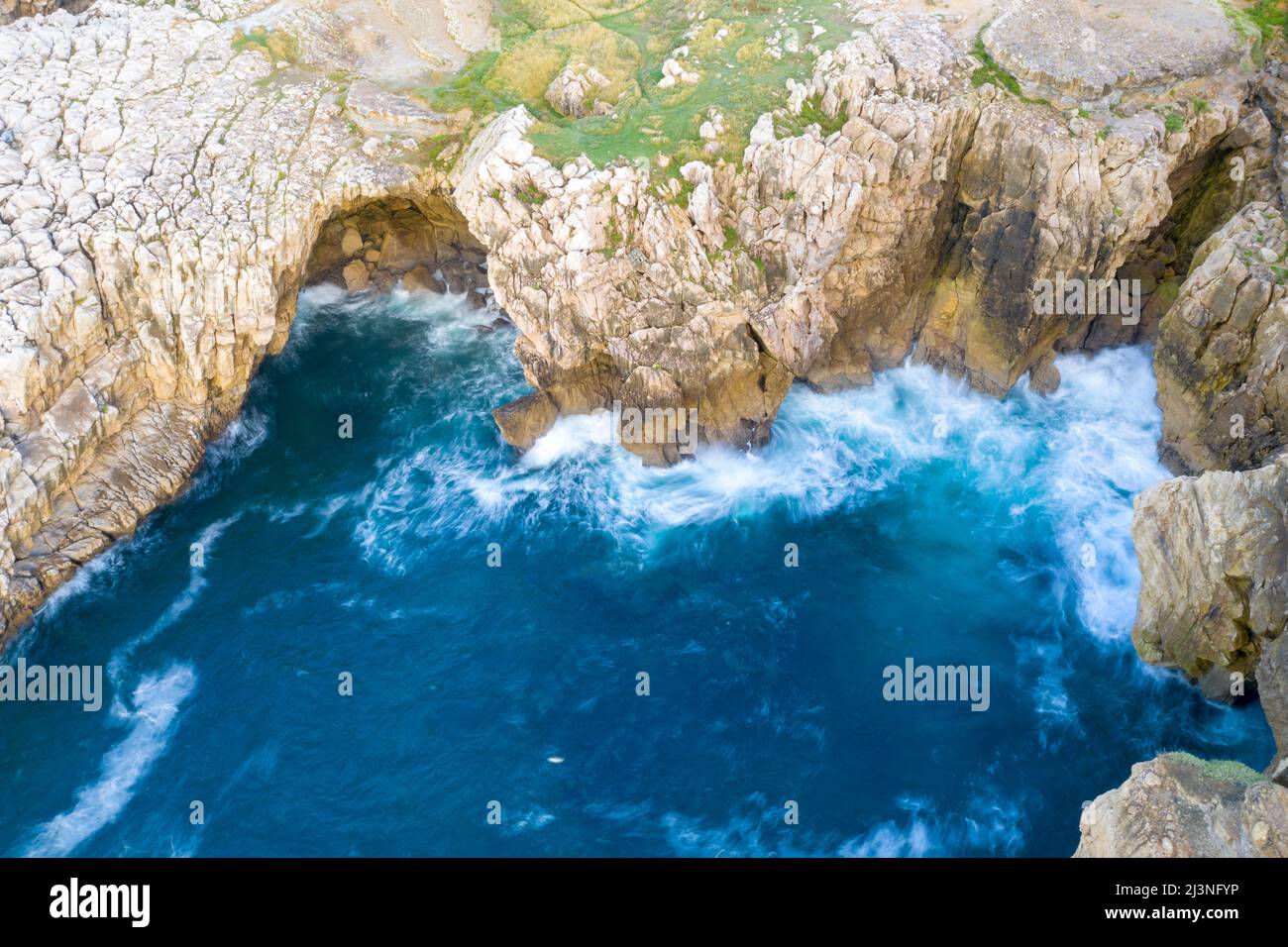 Vista aerea delle aspre scogliere e del mare turchese della costa cantabrica, delle spettacolari formazioni rocciose e delle potenti onde atlantiche nel nord della Spagna Foto Stock