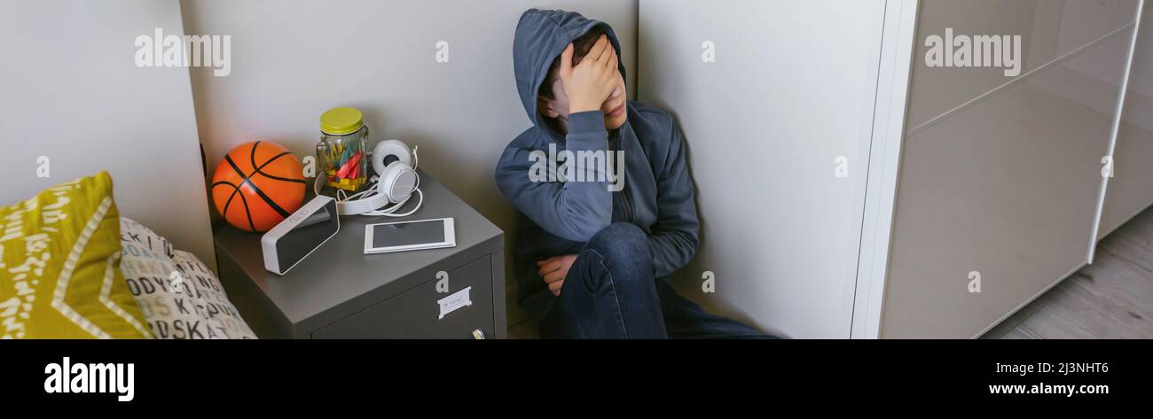 Adolescente depresso che siede sul pavimento nella sua camera da letto Foto Stock