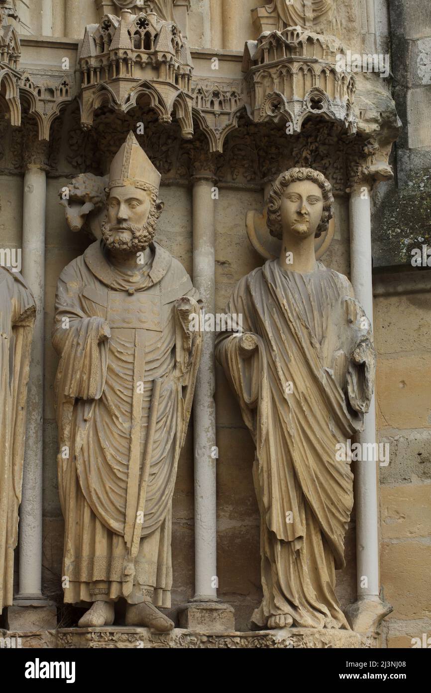 Saint Remigius di Reims raffigurato sul portale centrale della facciata nord della Cattedrale di Reims (Cathédrale Notre-Dame de Reims) a Reims, Francia. A sinistra è raffigurato San Remigio, mentre a destra è visibile la statua gotica di un angelo. Foto Stock