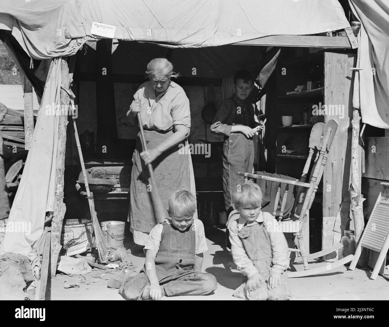 Donna anziana con tre dei suoi ventidue nipoti, campo migrante della contea di Kern, California. [Sign: 'Attenzione! Nessun visitatore. Per ordine del funzionario sanitario"]. Foto Stock