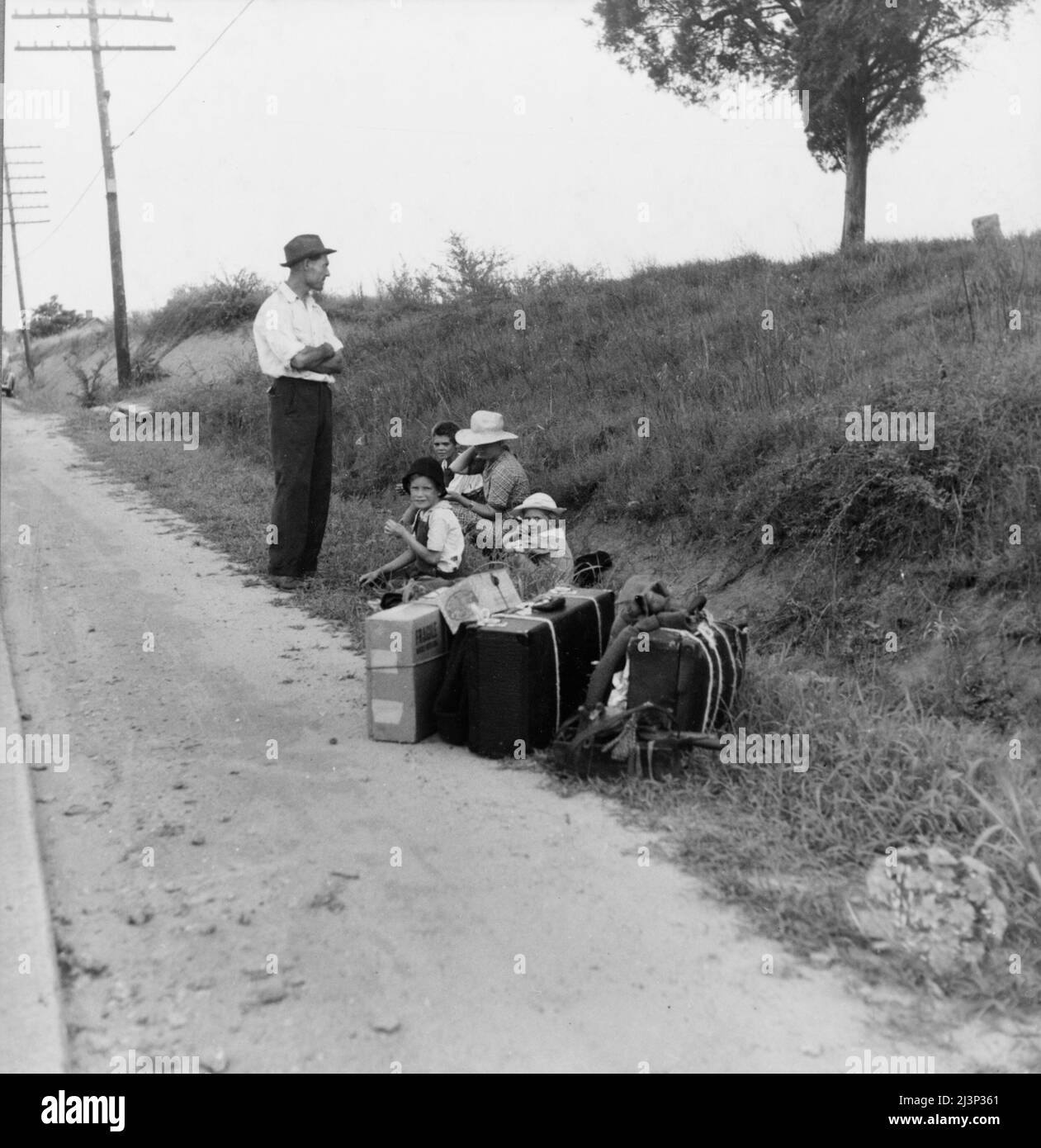 Una famiglia di hitchhiking in attesa lungo l'autostrada a Macon, Georgia. Il padre ripara macchine da cucire, tosaerba, ecc. sta lasciando Macon, dove è richiesta una licenza per tale lavoro (venticinque dollari) e tornare per Alabama. Foto Stock