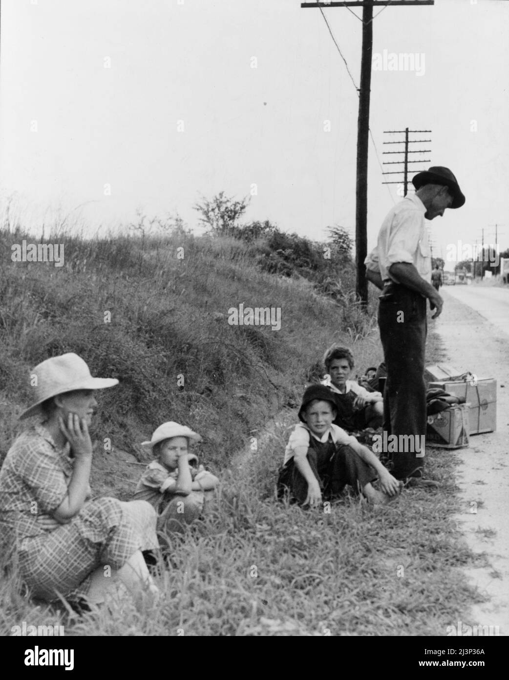 Una famiglia di hitchhiking in attesa lungo l'autostrada a Macon, Georgia. Il padre ripara macchine da cucire, tosaerba, ecc. sta lasciando Macon, dove è richiesta una licenza per tale lavoro (venticinque dollari) e tornare per Alabama. Foto Stock
