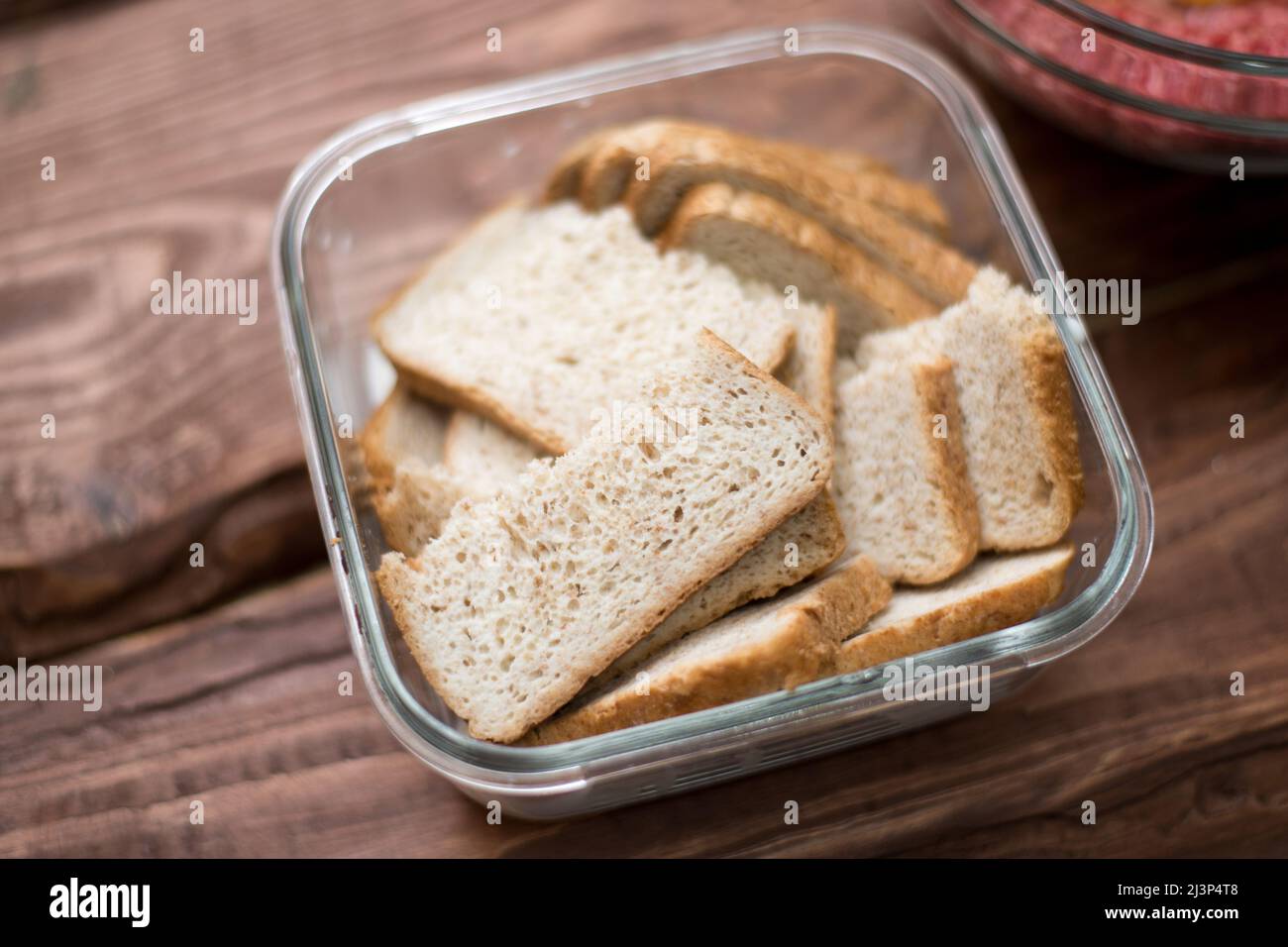 Pane immerso nel latte per preparare polpette. Foto Stock