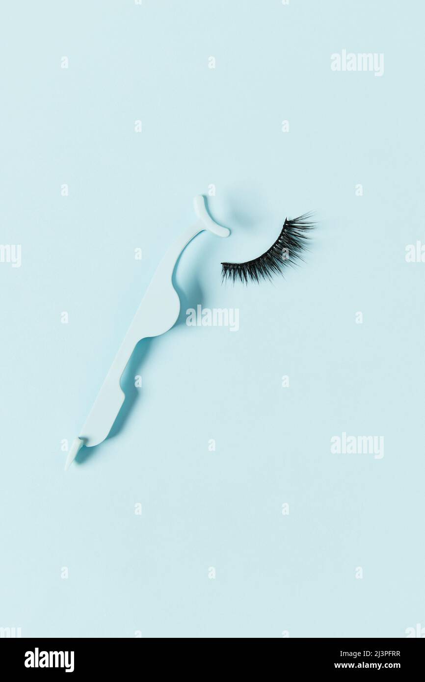 Piano Lay Top Visualizza le false ciglia e l'applicatore su sfondo blu Foto Stock