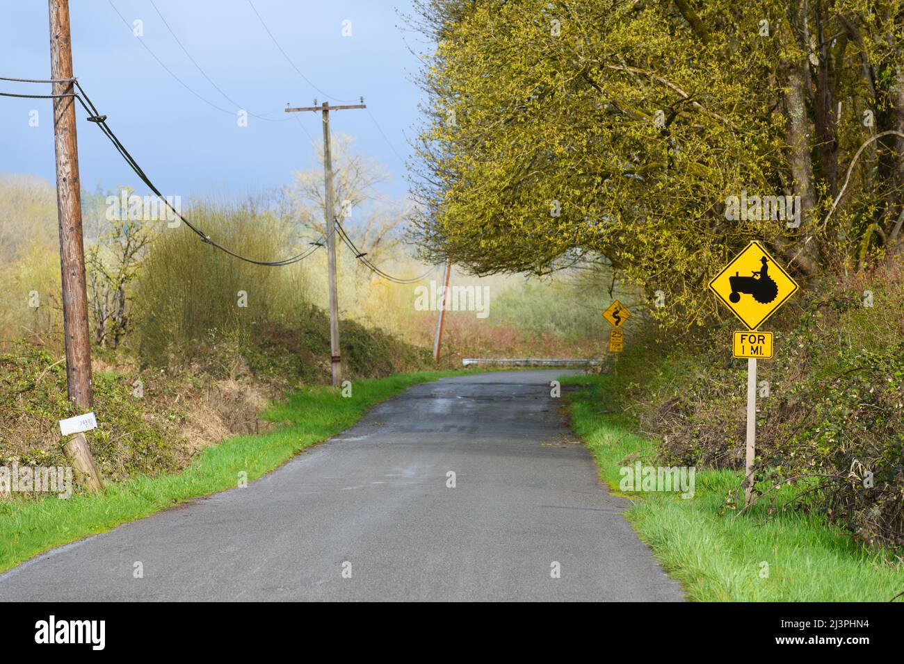 Strada di campagna negli Stati Uniti con un cartello con un trattore che indica l'attività agricola per un miglio Foto Stock