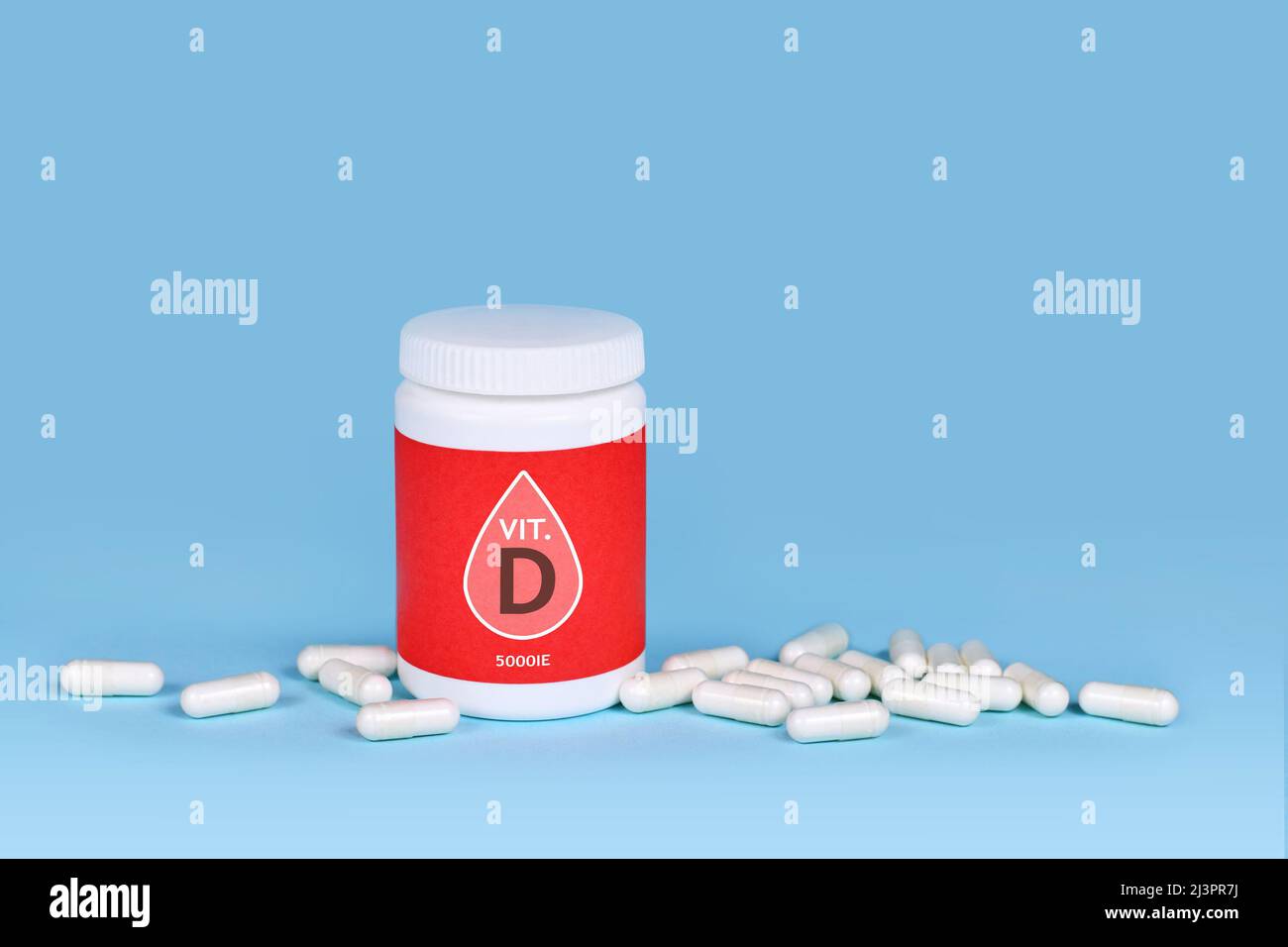 Integratore alimentare vitaminico D con contenitore con pillole su sfondo blu Foto Stock