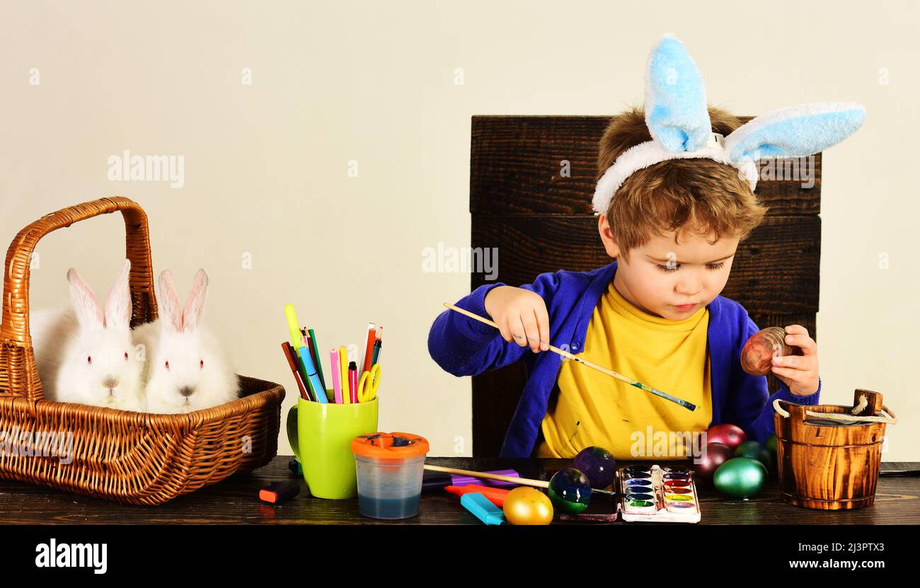 Bambino ragazzo in orecchie conigliate decorare le uova di Pasqua. Creatività dei bambini. Decorazione uova. Vacanze di primavera. Foto Stock