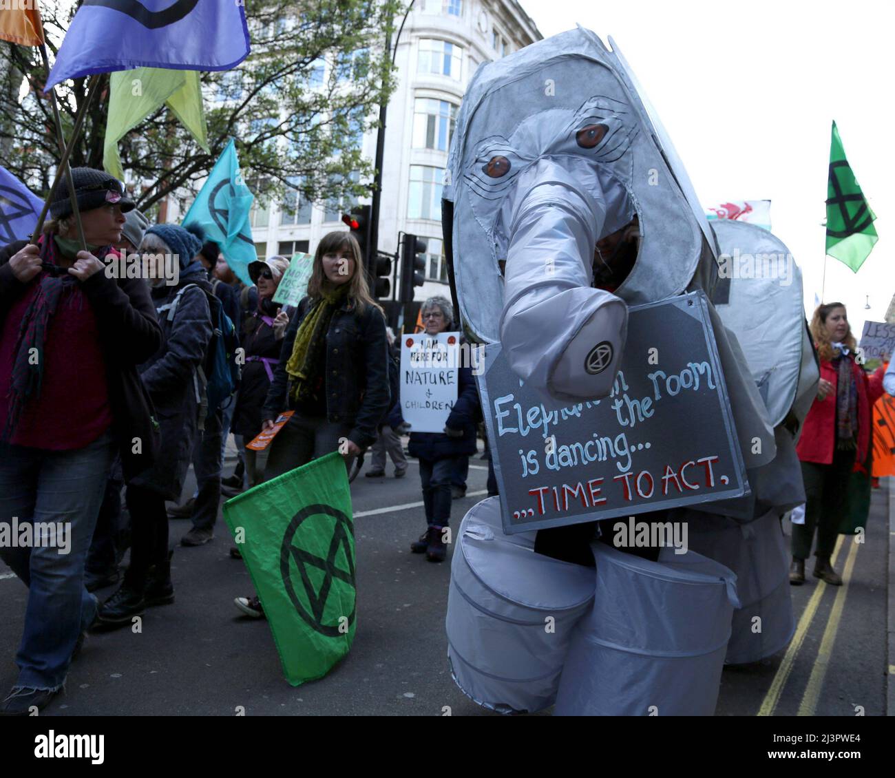 Il protesto della ribellione dell'estinzione, vestito con un costume da elefante, si abbattere a Oxford Street, Londra, come parte della loro azione contro il cambiamento climatico e l'uso di combustibili fossili. Il cartello recita 'quando l'elefante in camera sta ballando...è tempo di agire'.9th Aprile 2022. Anna Hatfield/Pathos Foto Stock