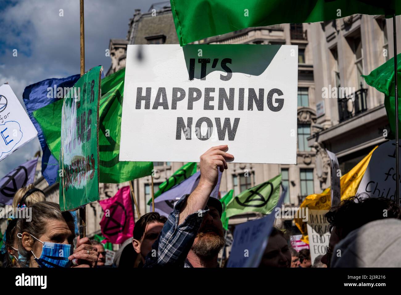 Sta accadendo ora placard, non saremo spettatori, una protesta della ribellione di estinzione che combatte per la giustizia climatica, nel centro di Londra, 09.04.2022, Londra, Inghilterra, REGNO UNITO Foto Stock