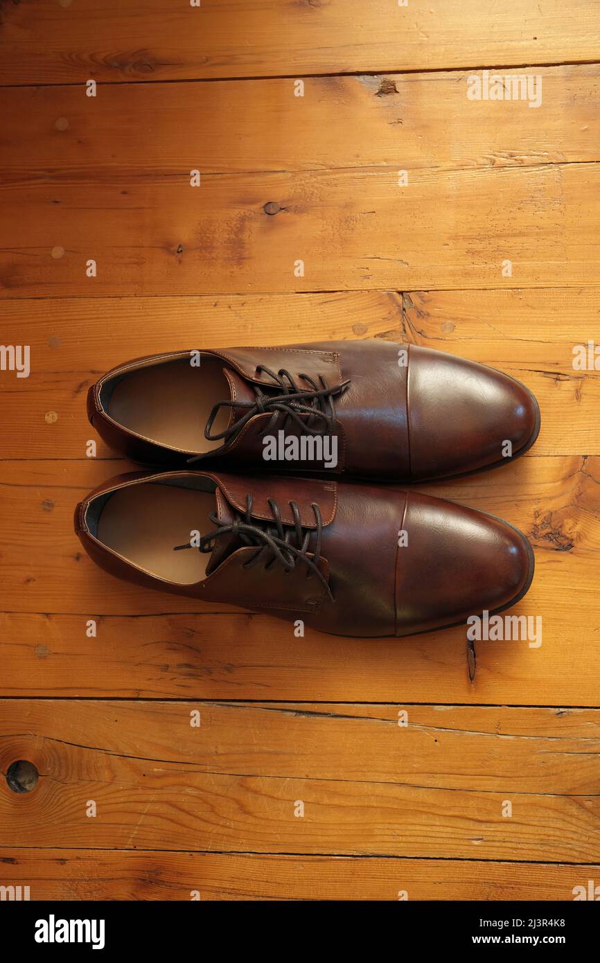 Eleganti e classiche scarpe di vestito in pelle marrone su un pavimento rustico in legno Foto Stock