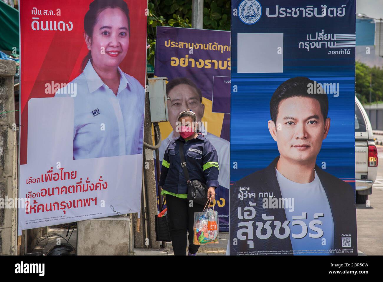 Un pedone passa accanto ai poster della campagna elettorale del governatore di Bangkok che mostrano i candidati Dutsanee Tiandech, Aswin Kwanmuang e Suchatvee Suwansawat durante i preparativi per le prossime elezioni gubernatoriali e consiglieri della città di Bangkok a Bangkok. L'undicesima elezione del governatorato di Bangkok si terrà il 22 maggio 2022, che è la prima elezione del governatorato di Bangkok in nove anni dal 2013, dopo che l'esercito ha conquistato il potere in un colpo di stato del 2014. Foto Stock