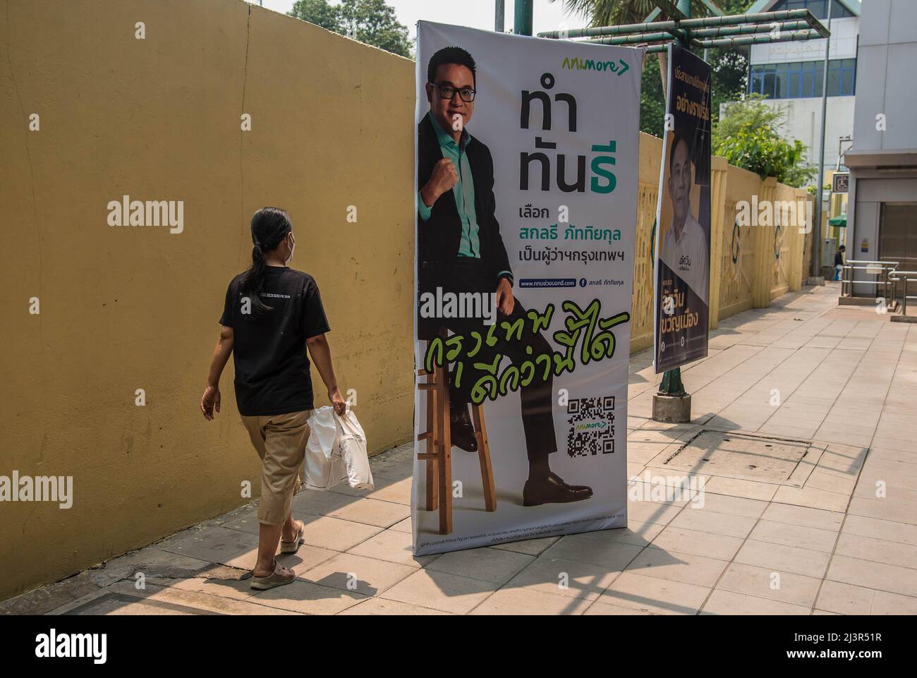 Un pedone passa accanto a un poster della campagna elettorale del governatore di Bangkok che mostra il candidato Sakontee Pattiyakul durante i preparativi per le imminenti elezioni gubernatoriali e consiglieri della città di Bangkok. L'undicesima elezione del governatorato di Bangkok si terrà il 22 maggio 2022, che è la prima elezione del governatorato di Bangkok in nove anni dal 2013, dopo che l'esercito ha conquistato il potere in un colpo di stato del 2014. Foto Stock