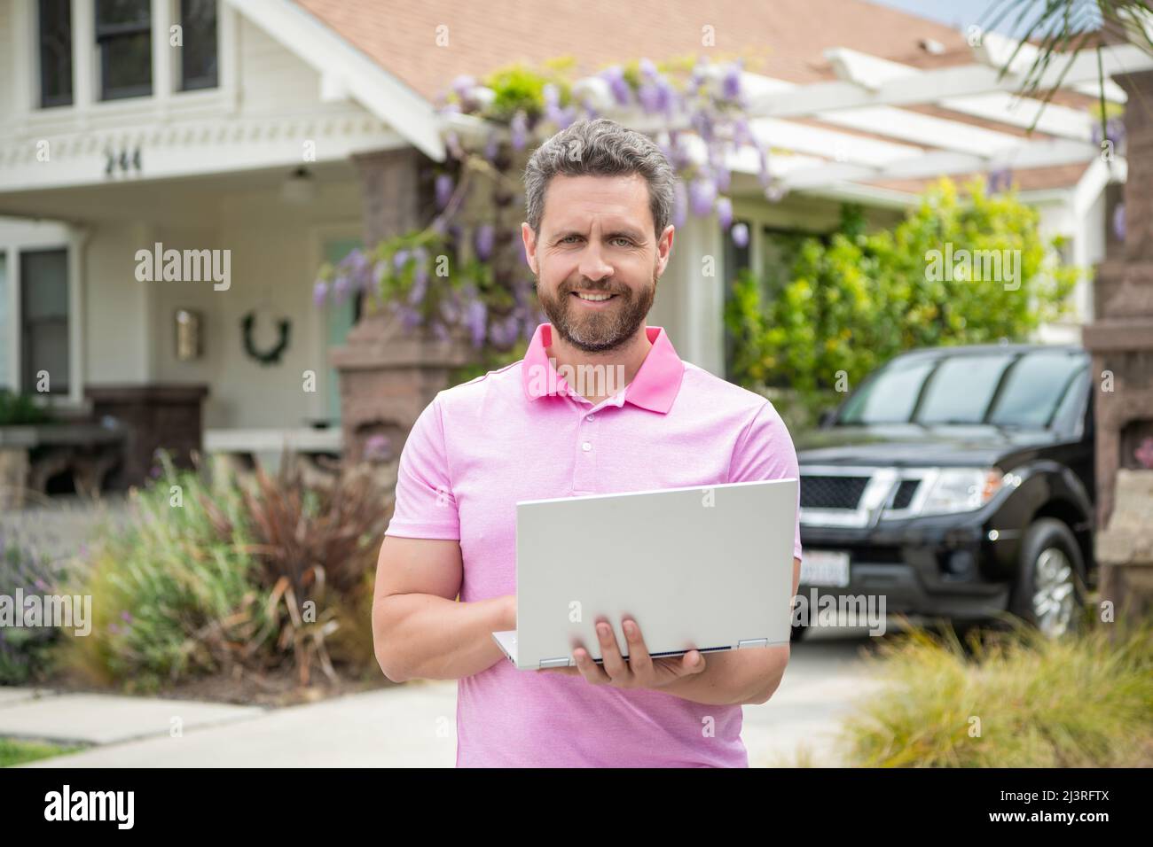 felice uomo bearded realtor acquistare casa online su laptop, presentazione Foto Stock