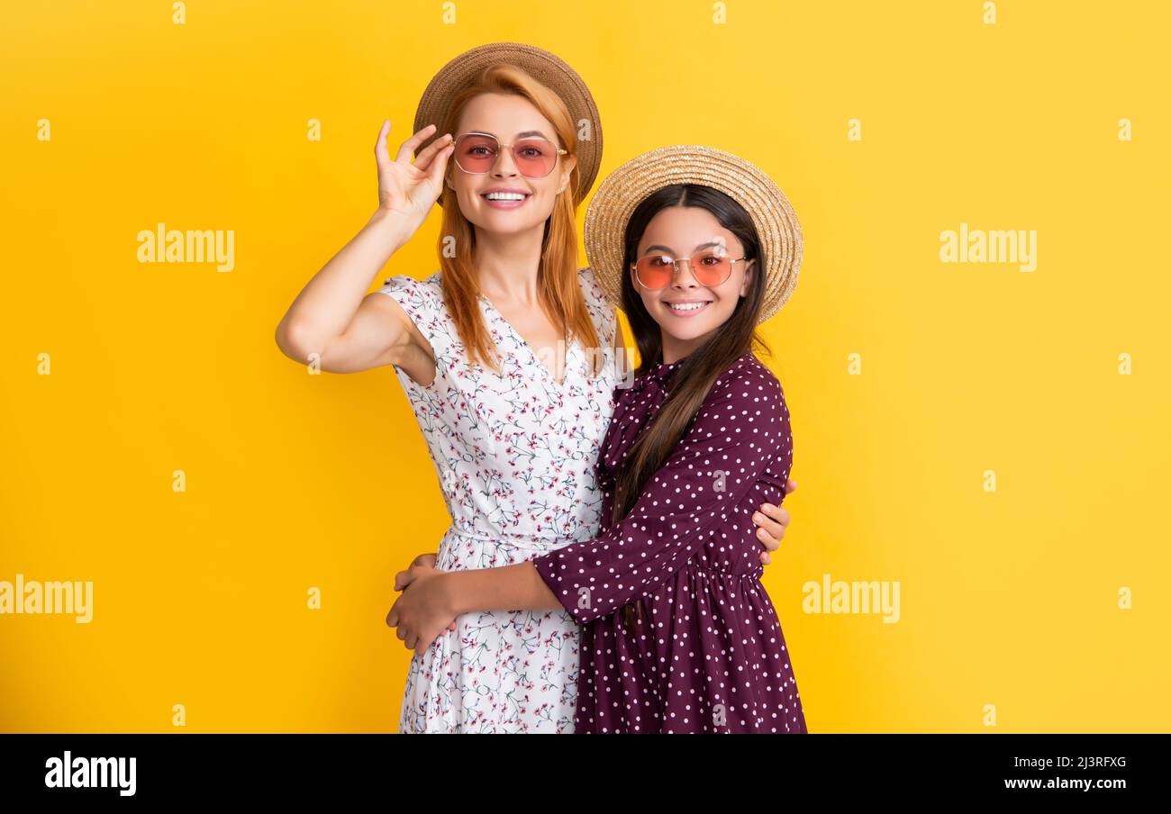 madre e figlia sorridono in cappello di paglia su sfondo giallo Foto Stock