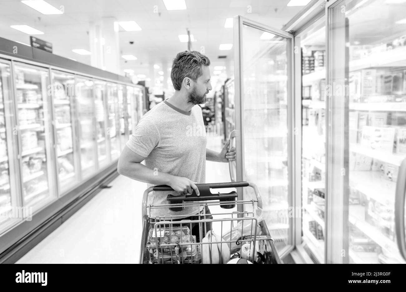 uomo con carrello di acquisto di cibo alla drogheria, consumo Foto Stock