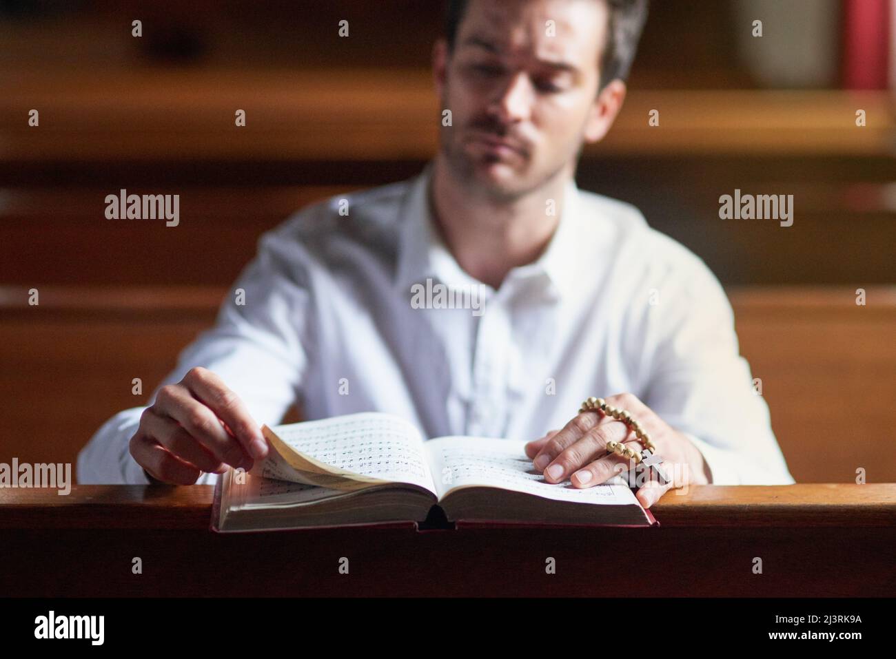 Ascoltare la voce di Dio attraverso il suo verso. Scatto di un giovane che legge la bibbia in chiesa. Foto Stock