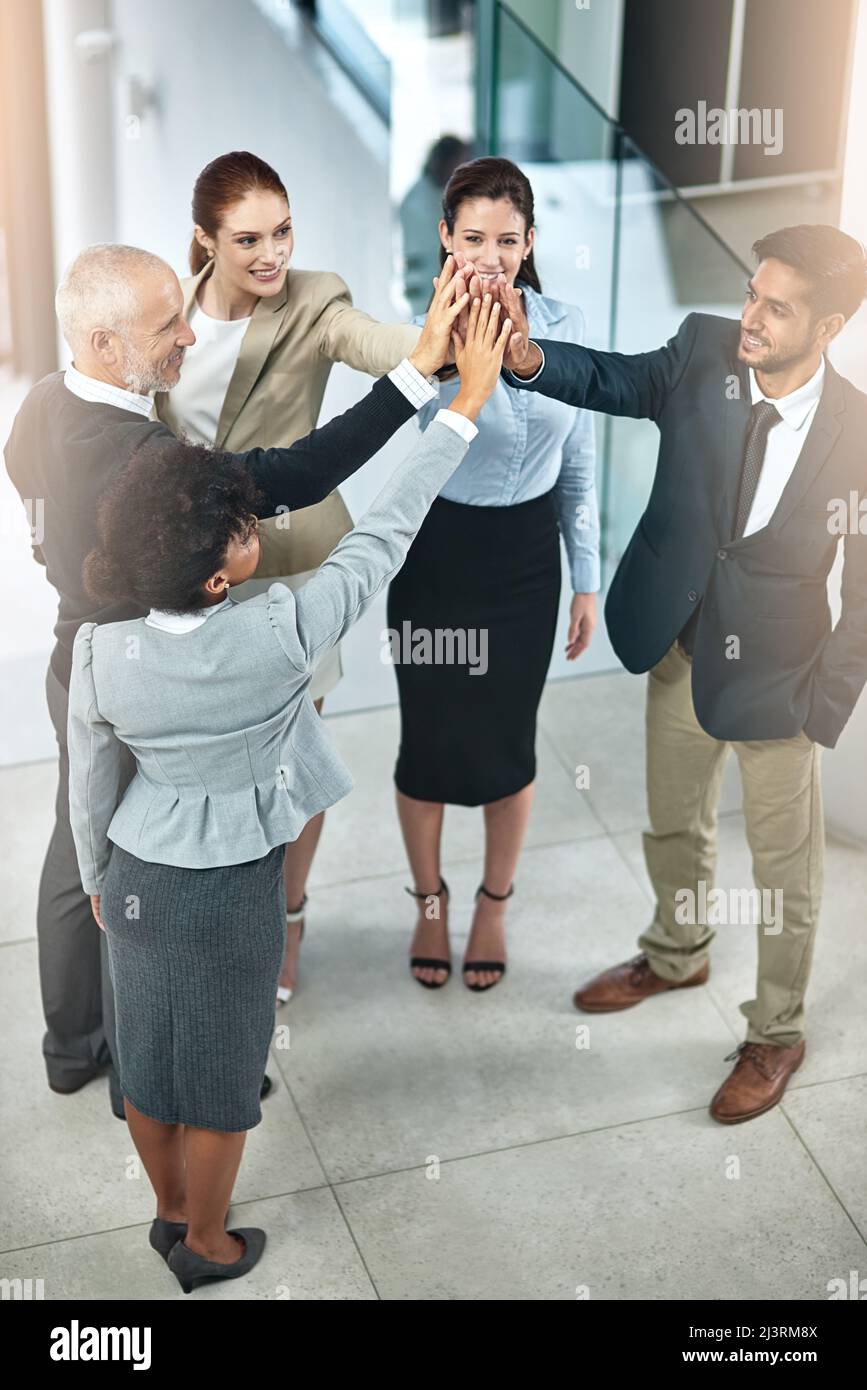 La motivazione dei dipendenti è fondamentale per mantenere una piacevole cultura d'ufficio. Colpo di un gruppo di uomini d'affari che dà un high-five. Foto Stock