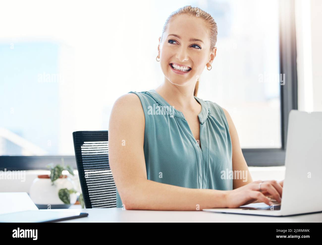 Questo buon umore è stato sponsorizzato dalla passione. Scatto di una giovane donna d'affari attraente seduta da sola in ufficio e utilizzando il suo laptop. Foto Stock