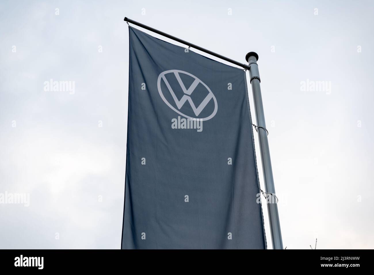 Volkswagen AG logo su una bandiera alta appesa molto alto. Emblema VW su un banner tessile blu scuro che si muove nel vento. Industria automobilistica in Germania. Foto Stock