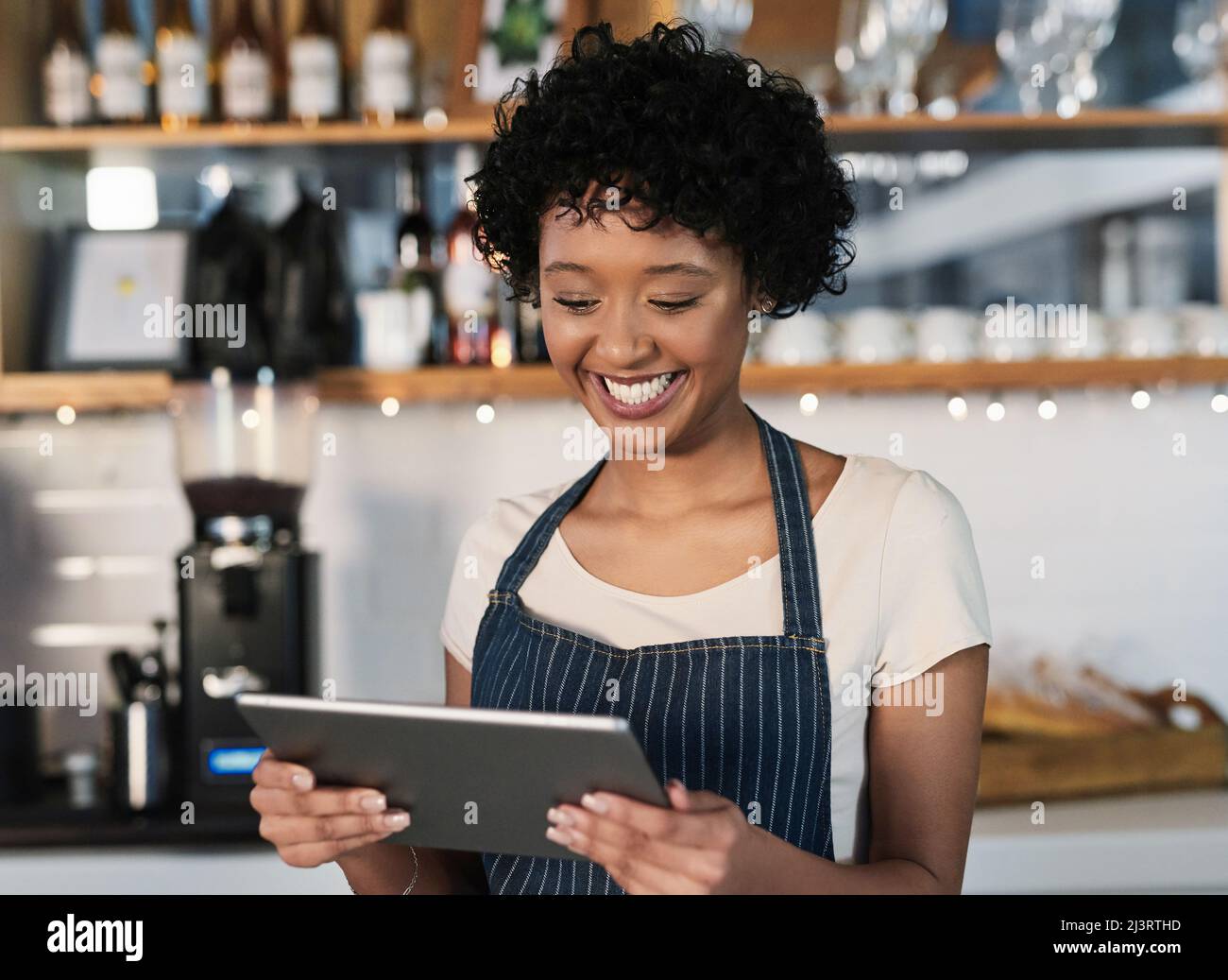 Sfruttare gli strumenti tecnologici per incrementare le vendite. Scatto di una giovane donna che usa un tablet digitale mentre lavora in un bar. Foto Stock