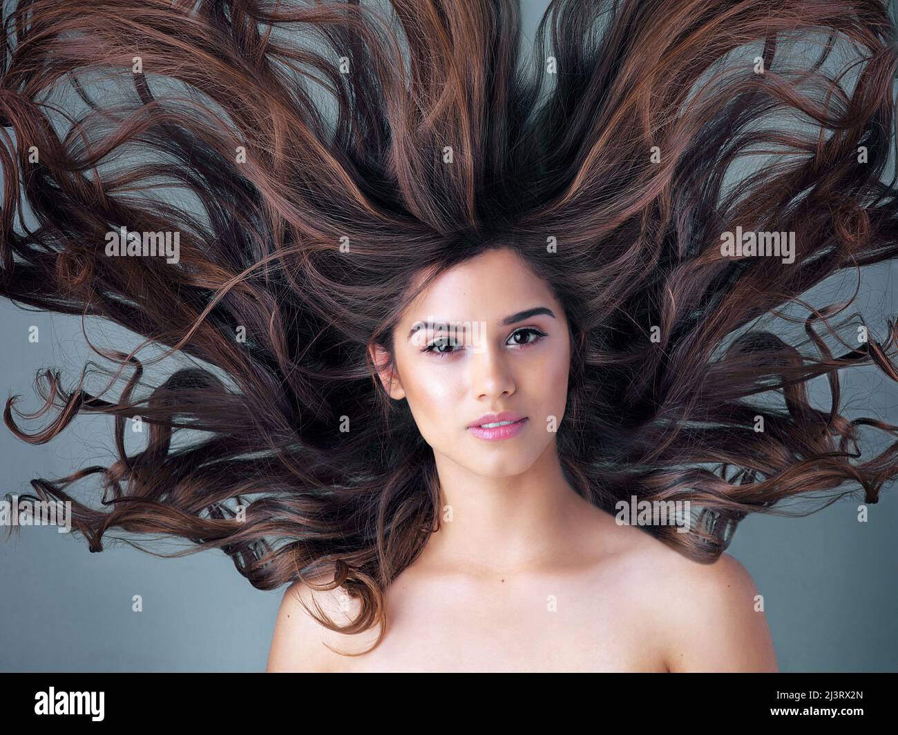 Capelli grandi, grandi sogni. Studio girato di una bella giovane donna in posa su uno sfondo grigio. Foto Stock