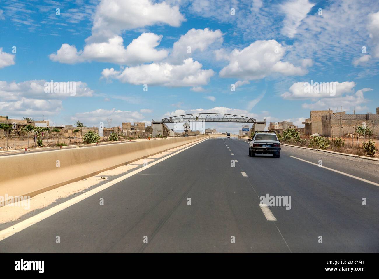 Moderna autostrada divisa a quattro corsie vicino a Dakar, Senegal. Ponte pedonale in distanza. Foto Stock