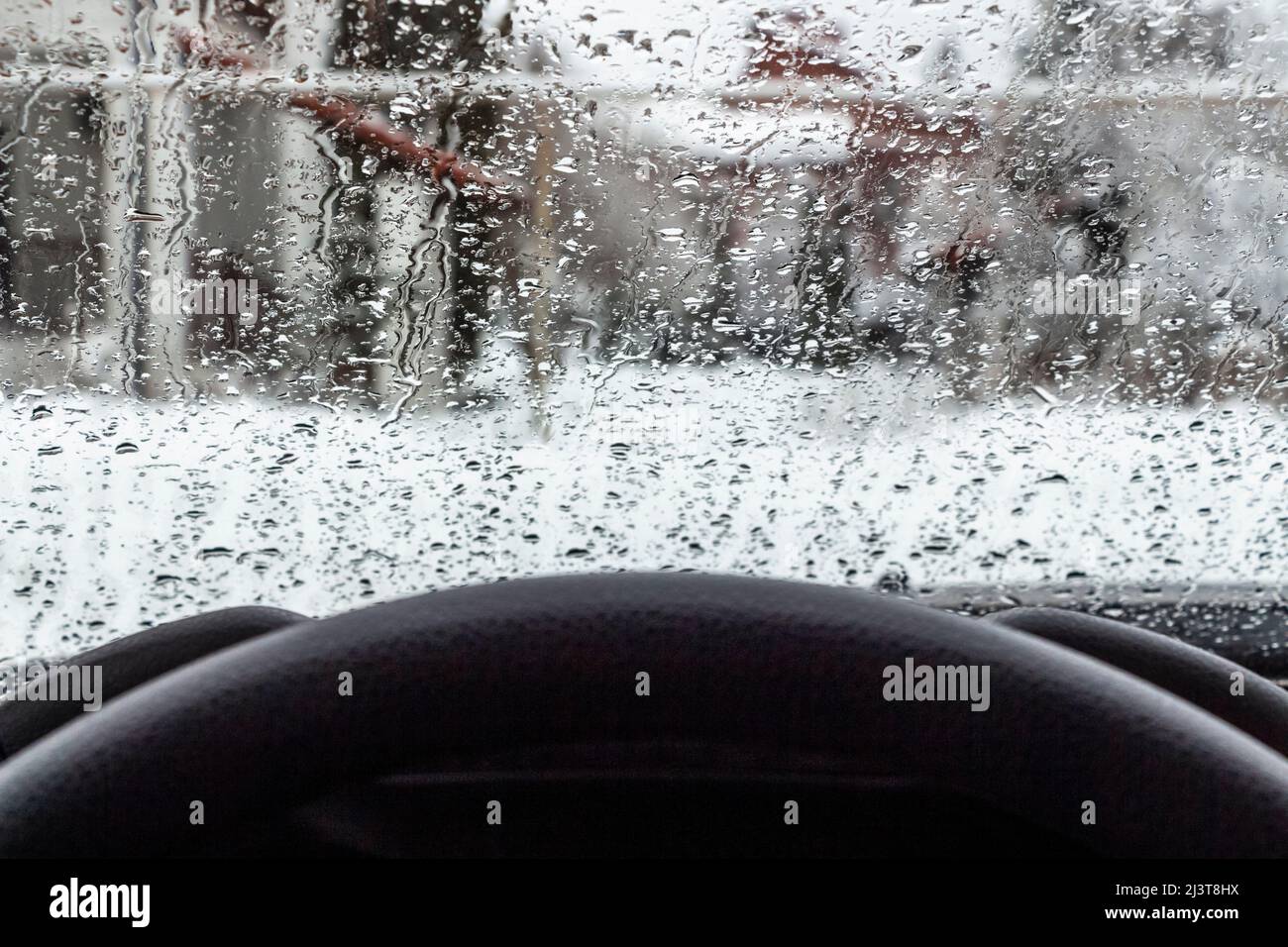 Gocce di fiocchi di neve fusi sul parabrezza di un'auto. Foto Stock