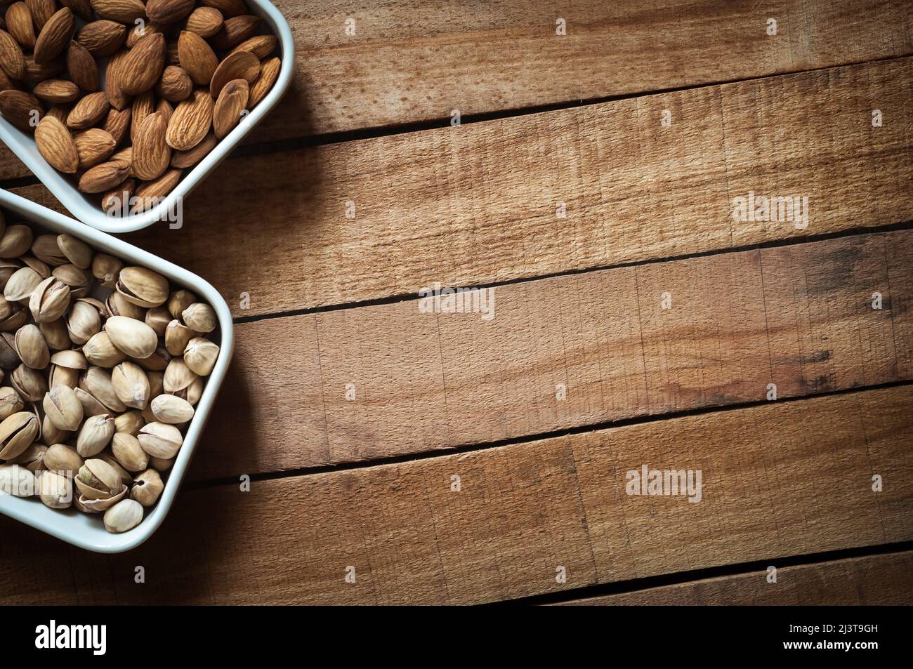 I chicchi di mandorle e i pistacchi si trovano su piattini bianchi Foto Stock