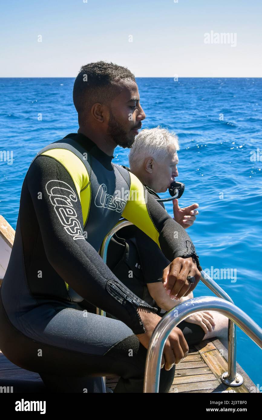 Subacquei prima di tuffarsi. Lezione di immersione in acqua aperta. Gli uomini in tuta subacquea si stanno preparando a tuffarsi in mare profondo. Hurghada, Egitto – 2021 ottobre Foto Stock