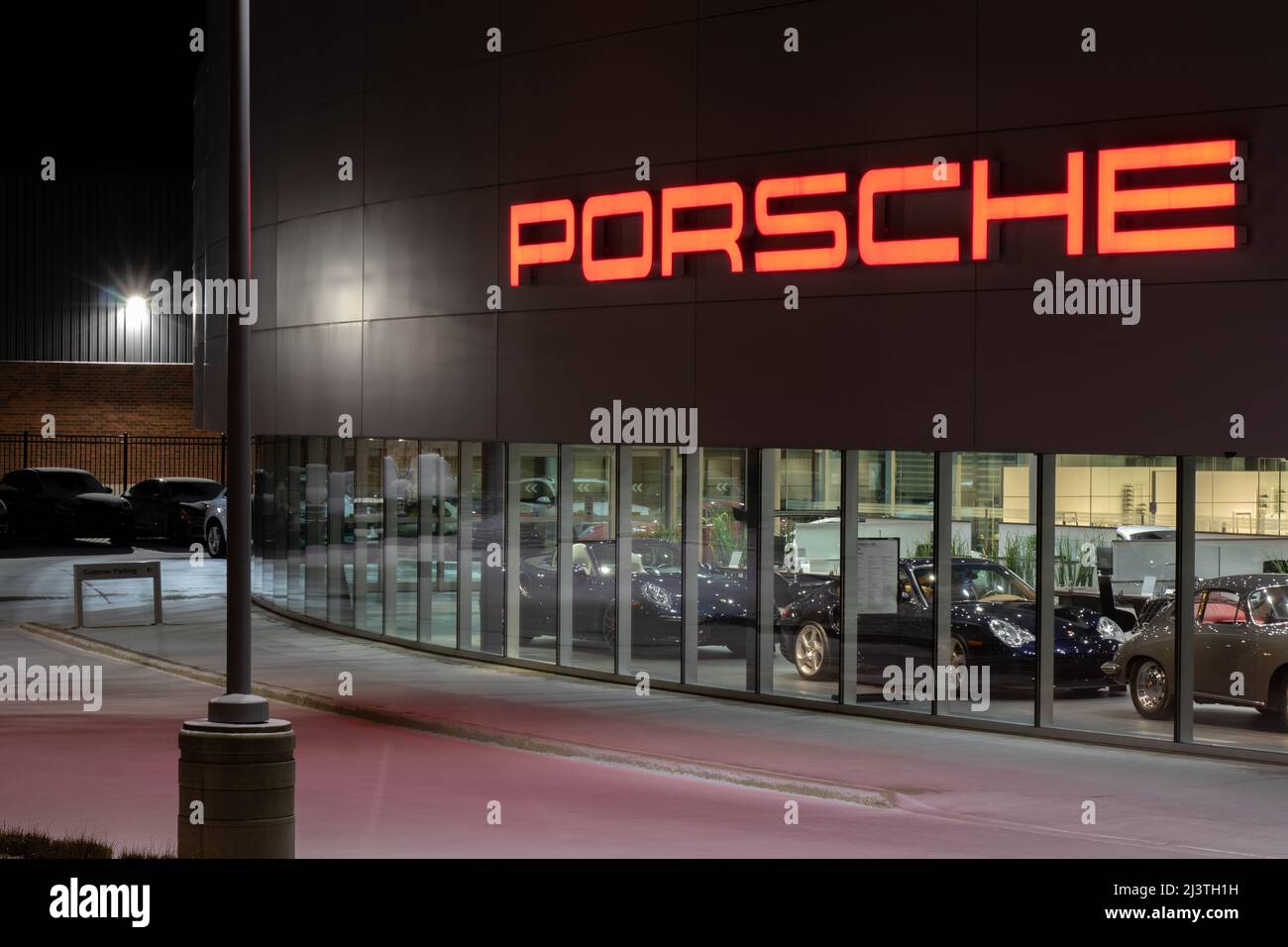 La parte anteriore di una Porsche, un costruttore di auto di lusso e prestazioni, concessionaria di notte. Foto Stock