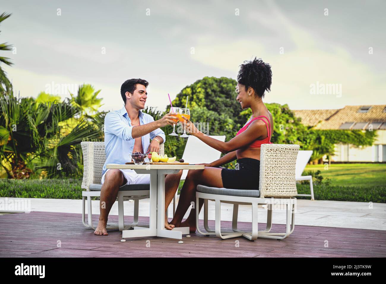 Coppia gioiosa di vacanza facendo colazione seduti su un tavolo in terrazza - sposi novelli toast cocktail di frutta nel lussuoso patio del resort Foto Stock