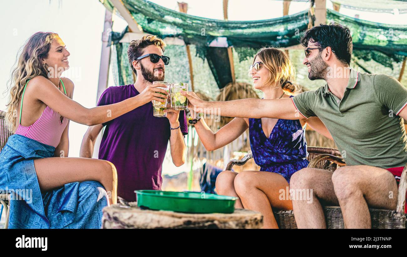 I migliori amici bevono cocktail sulla spiaggia e tostano durante l'happy hour. Foto Stock