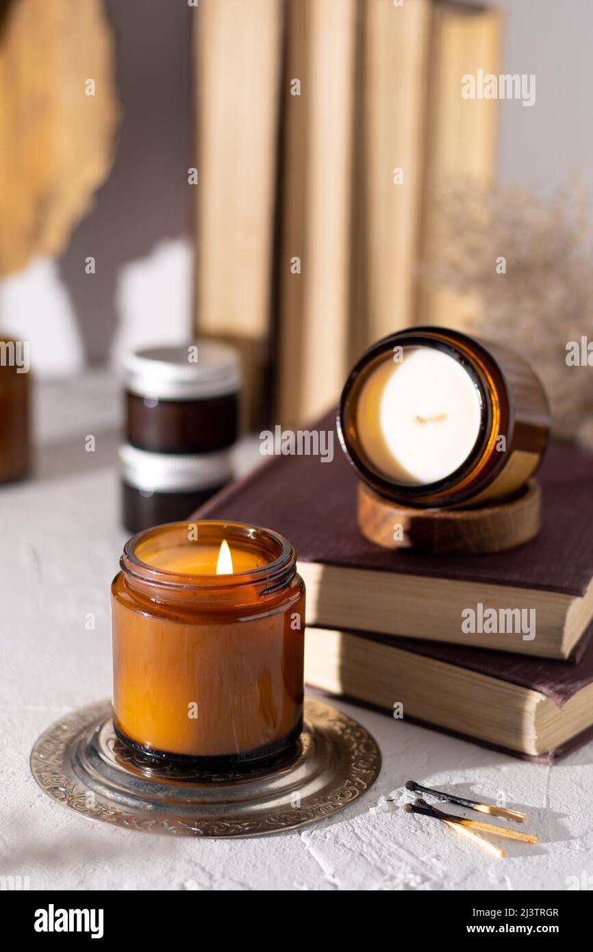 Un set di candele aromatiche diverse in vasetti di vetro marrone. Candela  profumata fatta a mano. Le candele di soia stanno bruciando in un vaso.  Aromaterapia e relax in spa e casa.