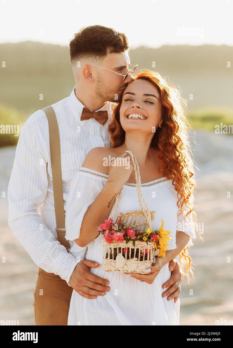 Il ragazzo bacia la testa della sua bella ragazza al tramonto Foto Stock