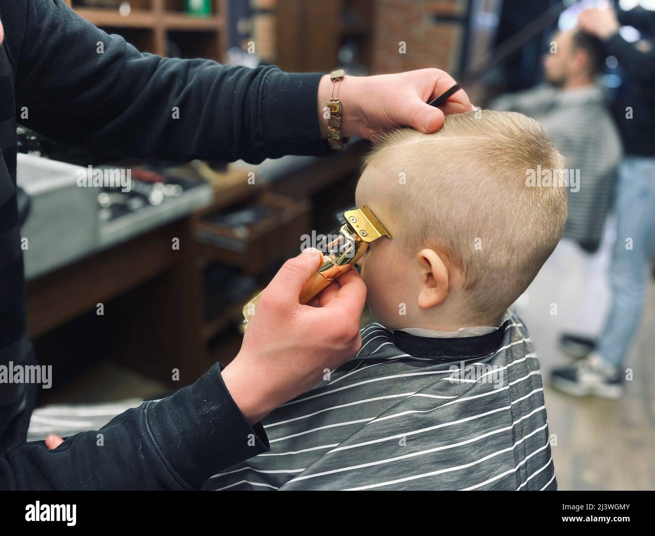 Master taglia i capelli di un ragazzino in un barbiere Foto Stock