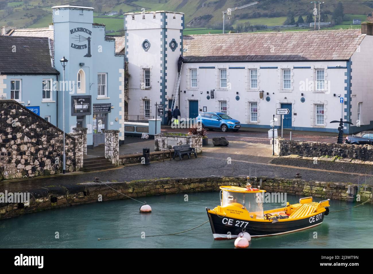 Operai che menedano un tetto nel villaggio della contea di Antrim di Carnlough Irlanda del Nord. Vista sul villaggio e barche nel porto di Carnlough. Foto Stock