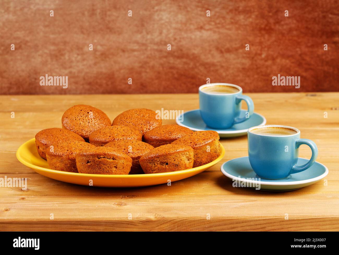 Tortini fatti in casa appena sfornati e due tazze di caffè espresso su un tavolo di legno. Foto Stock