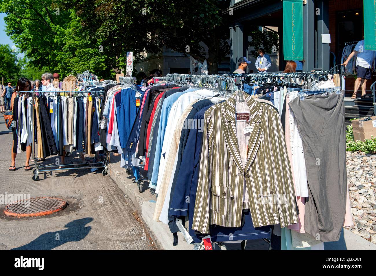 Ottawa, Canada - 26 maggio 2012: La gente sfoglia i vestiti usati sulla cremagliera alla vendita annuale del garage del quartiere di Glebe che ha luogo per parecchi blocchi M Foto Stock