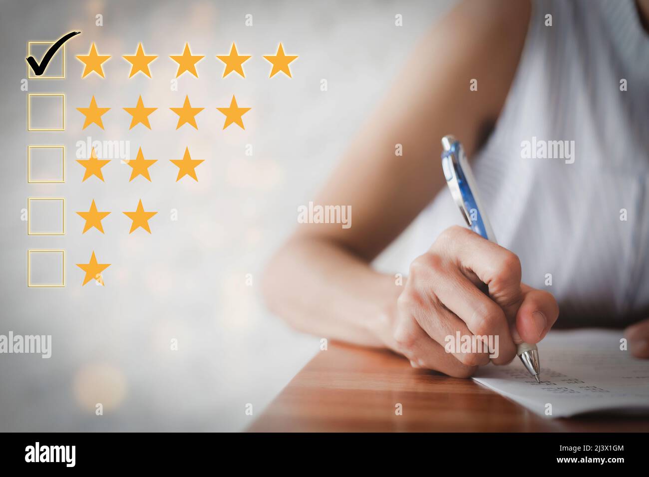 Mano femminile utilizzando una penna per compilare un questionario. Questionario sulla soddisfazione del cliente. Valutazione a cinque stelle. Selezionare la casella cinque stelle. Emo positivo Foto Stock