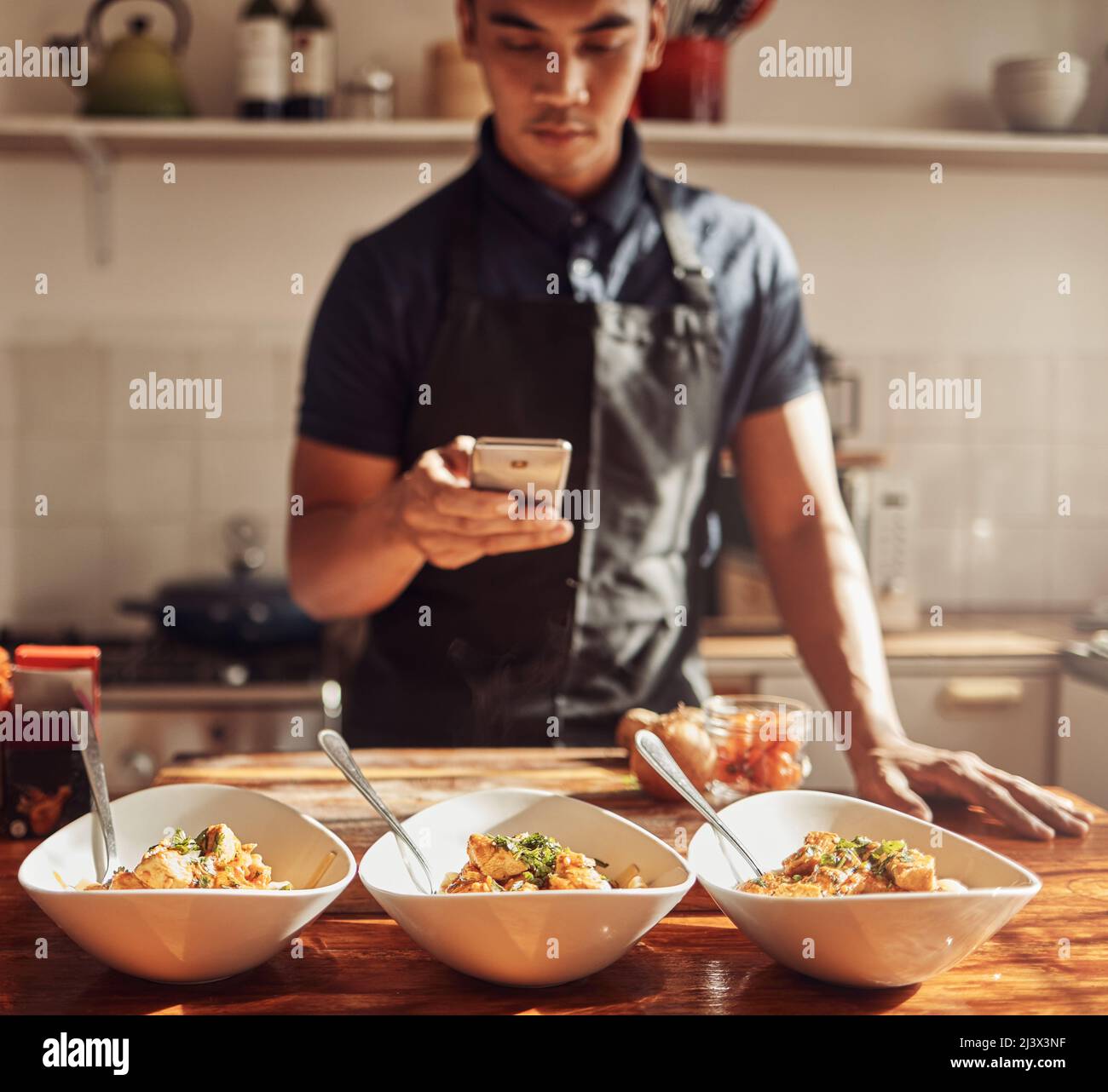 Il wiz culinario colpisce ancora. Scatto di un giovane uomo con uno smartphone per scattare foto di un pasto sano che ha preparato a casa. Foto Stock