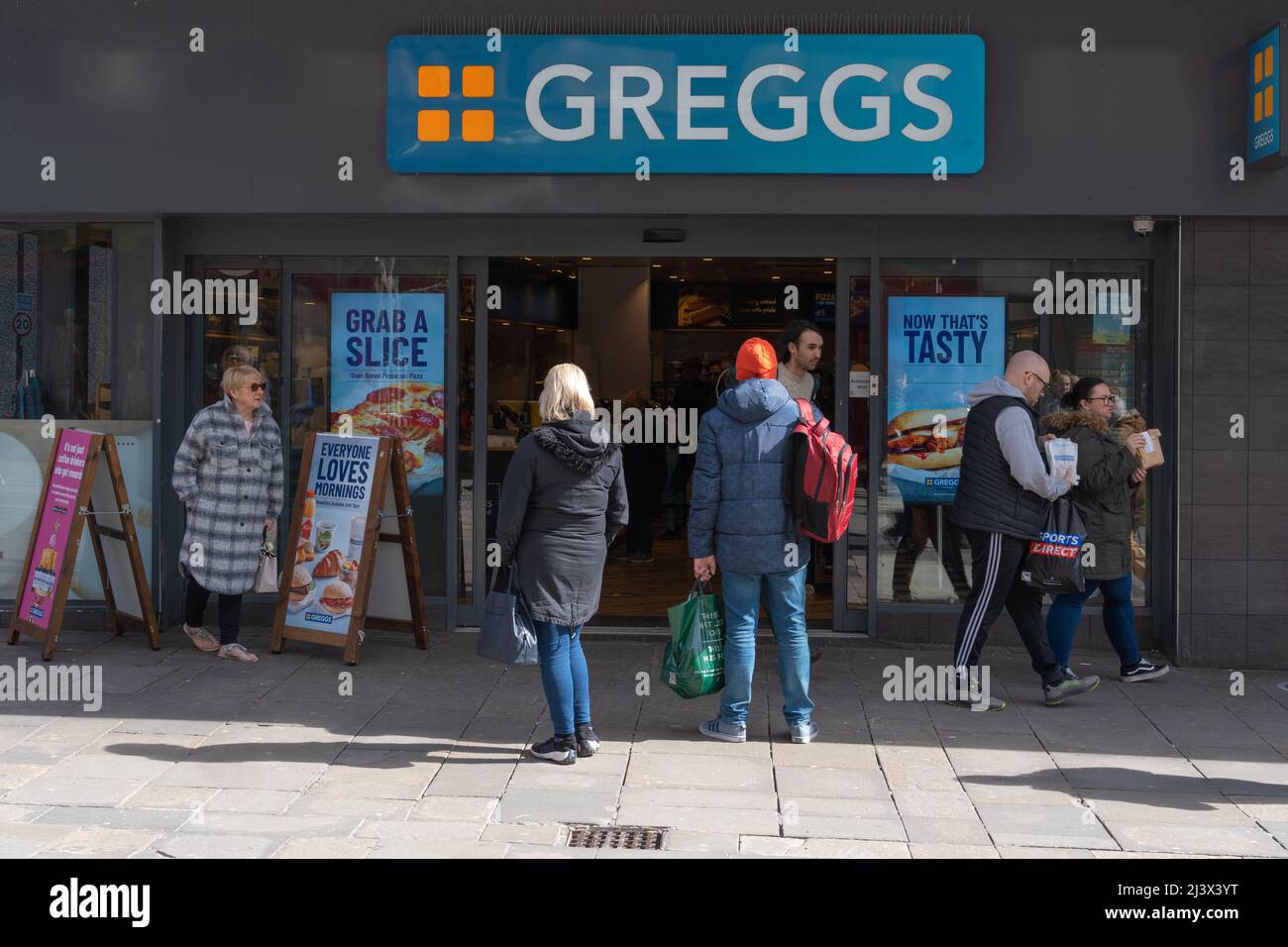 Persone che entreranno e uscendo da Greggs The Bakers a pranzo in un sabato di primavera a Newcastle upon Tyne, Regno Unito. Foto Stock