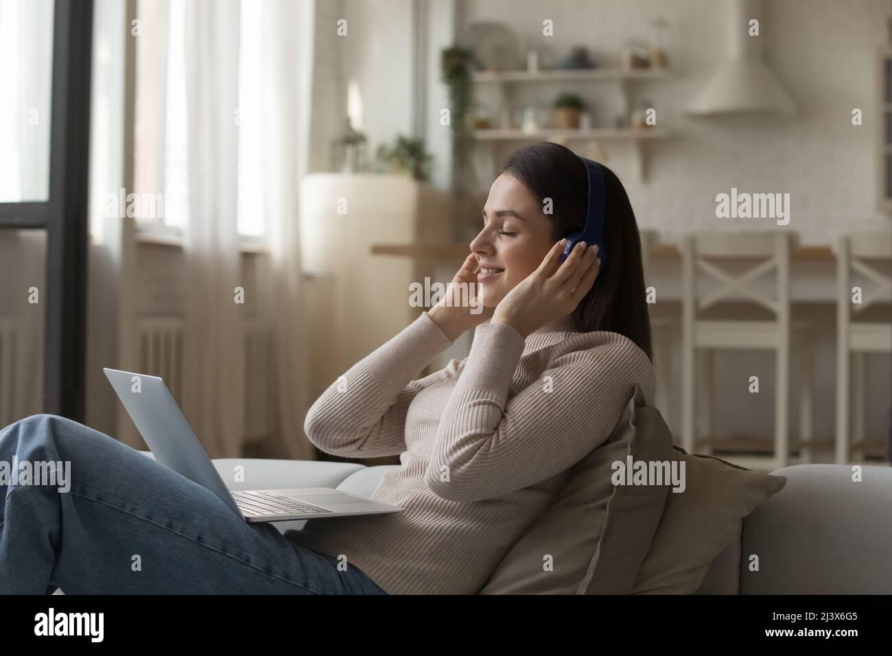 Felice calma bella giovane donna che tocca le cuffie wireless Foto Stock