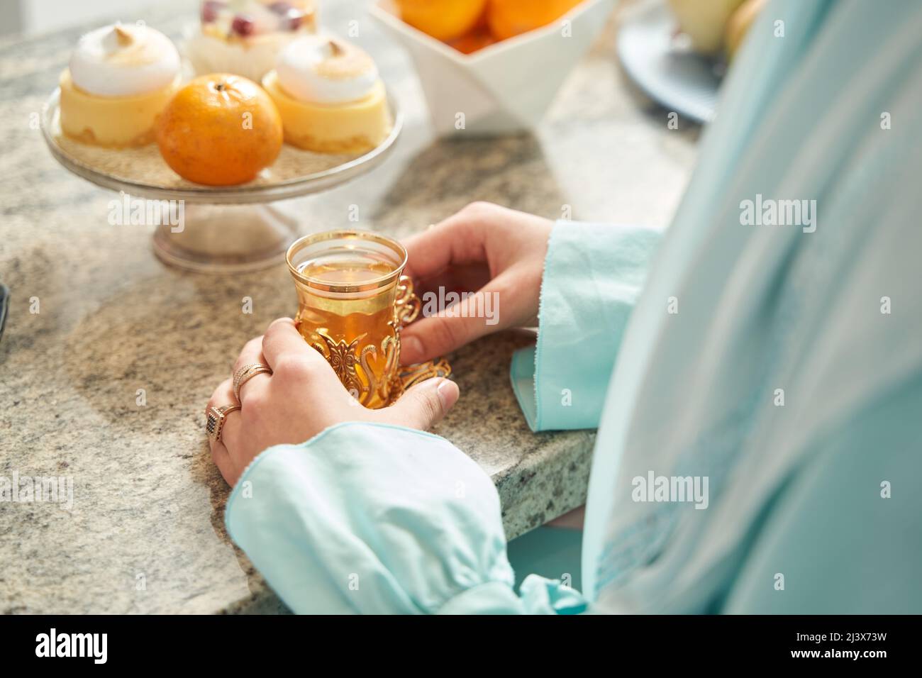 Donna non riconosciuta che ha il tè caldo con la pasticceria Foto Stock