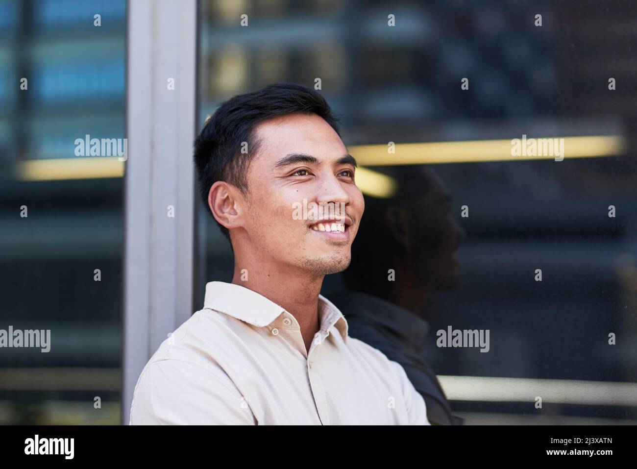 Ritratto di un giovane uomo d'affari del Sud Est asiatico fuori da una finestra d'ufficio Foto Stock