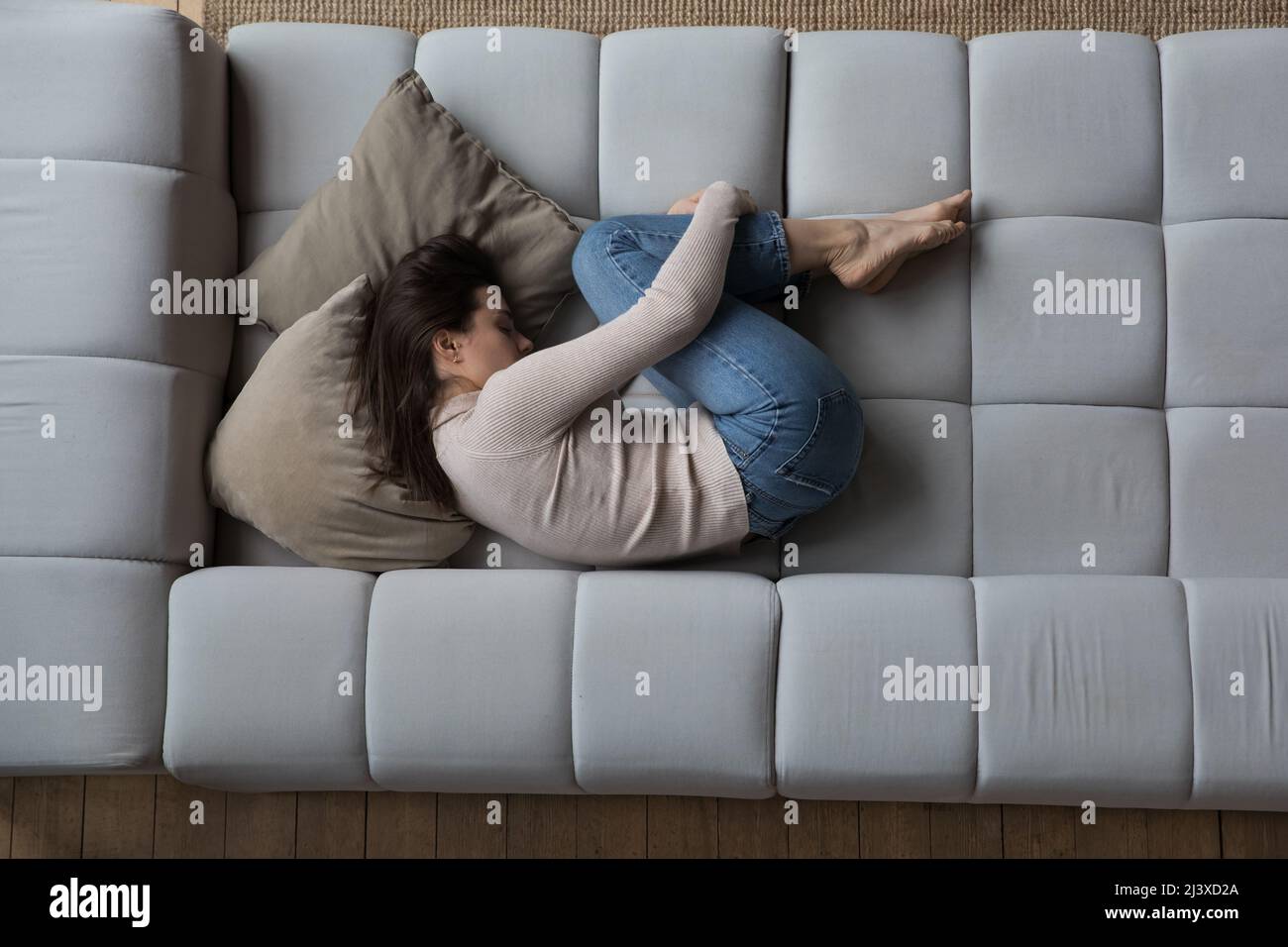 Frustrata ragazza depressa millennial sdraiata in posa embrione sul divano Foto Stock